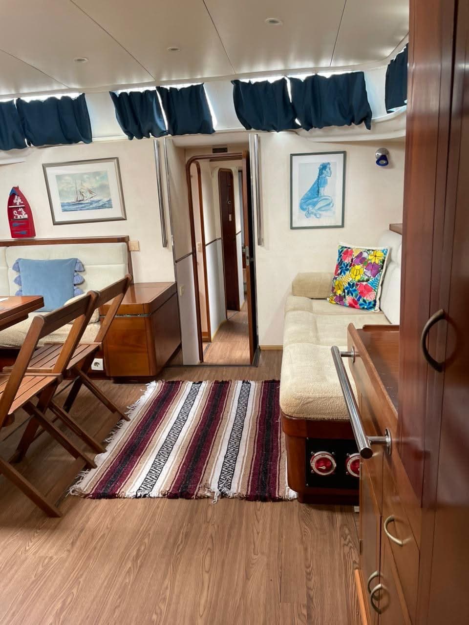 Flying Wing salon with teak joinery, framed clipper print, and cream upholstery